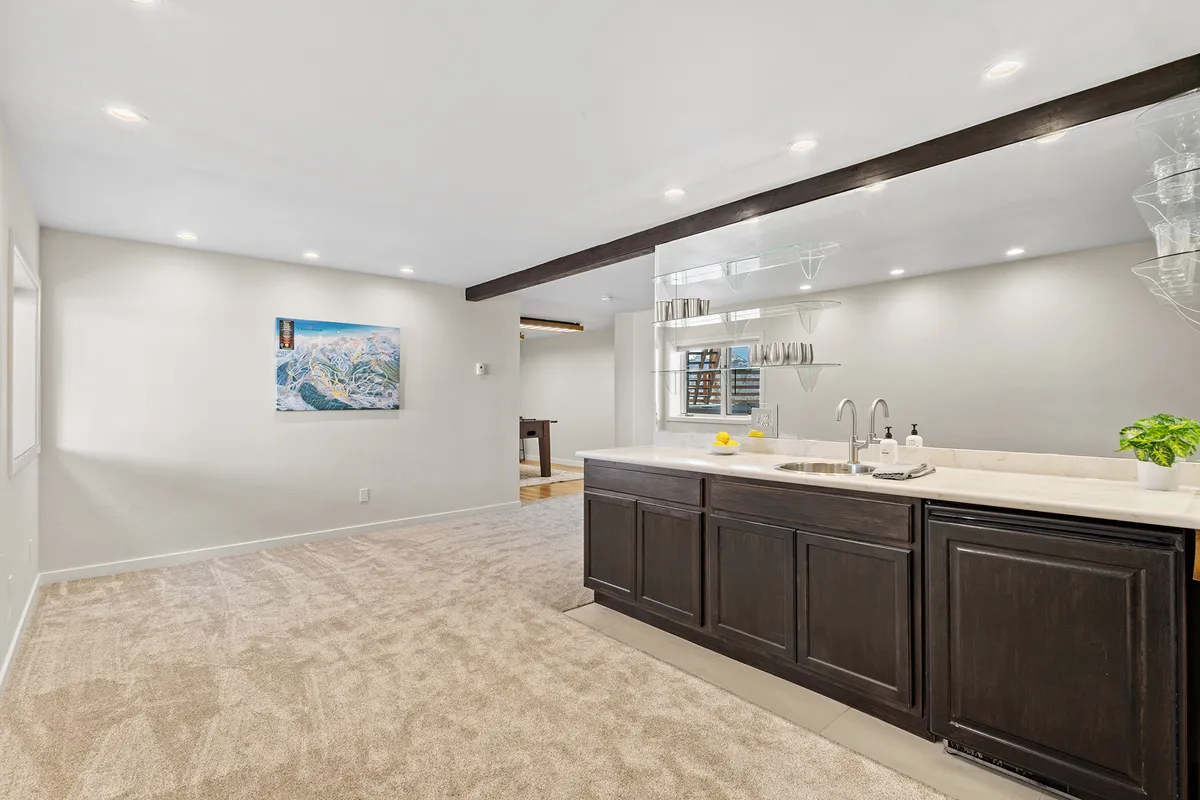 A stylish kitchen bar area with modern cabinetry and artwork, designed for casual entertaining and socializing. The bar is well-lit and welcoming, suggesting a perfect spot for mixing drinks or enjoying a nightcap.