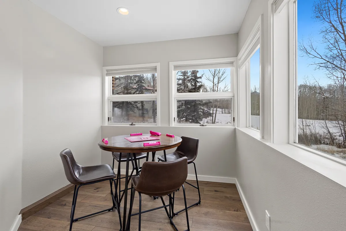 A cheerful breakfast nook featuring a round table and four chairs, set by tall windows that flood the space with light. The area feels intimate and perfect for morning coffee, casual meals, or family game nights.