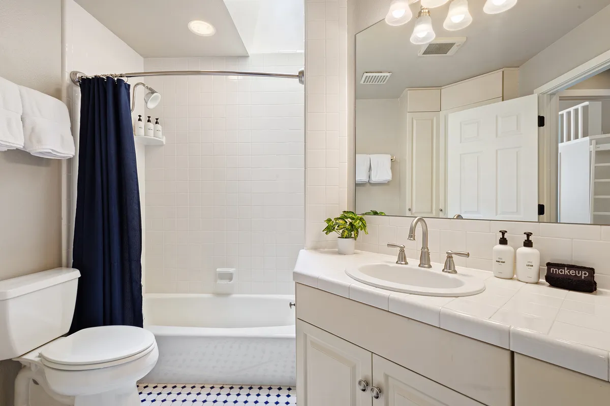 A half bath with a vanity, sink, mirror, shower area, and towel rack. The space is clean and refreshing, ideal for quick freshening up after games or before heading upstairs.