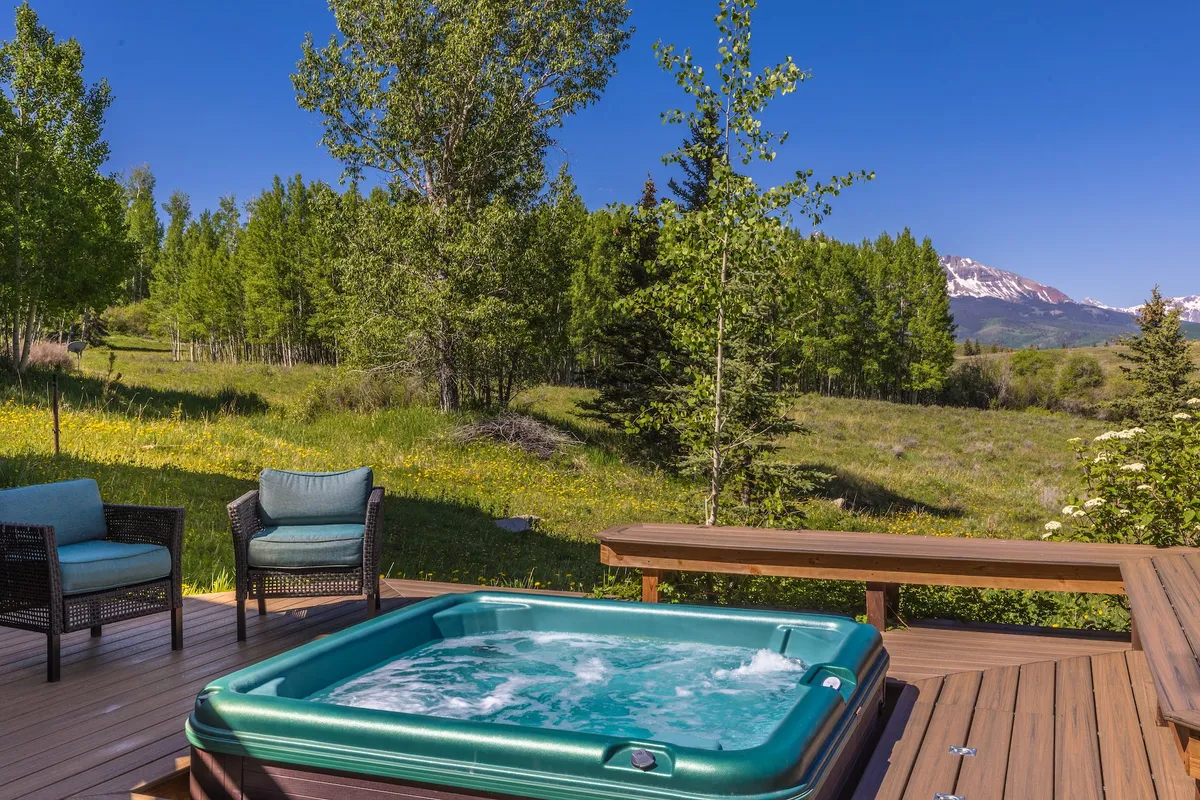 A spacious wooden deck with a hot tub and comfortable seating, all oriented toward dramatic mountain views. The outdoor area is seamlessly connected to the interior, offering a tranquil spot for après-ski relaxation or sharing stories under the stars.